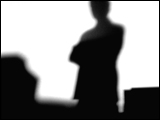 Video Clip - Human figures depicted in black in front of a white background; one person standing while other sit at their workstations