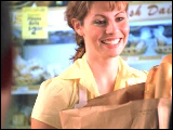 Video Clip - A cashier in a grocery store passing groceries to a customer
