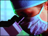 Video Clip - Woman doctor prepped up looking into a microscope